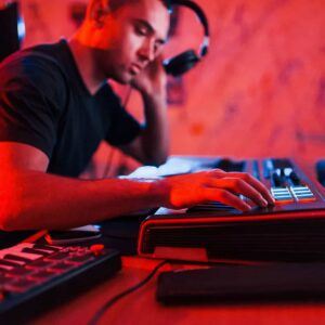 Un musicien en formation sur la musique assistée par ordinateur, sélectionnant un son sur un synthétiseur tout en utilisant un casque audio.