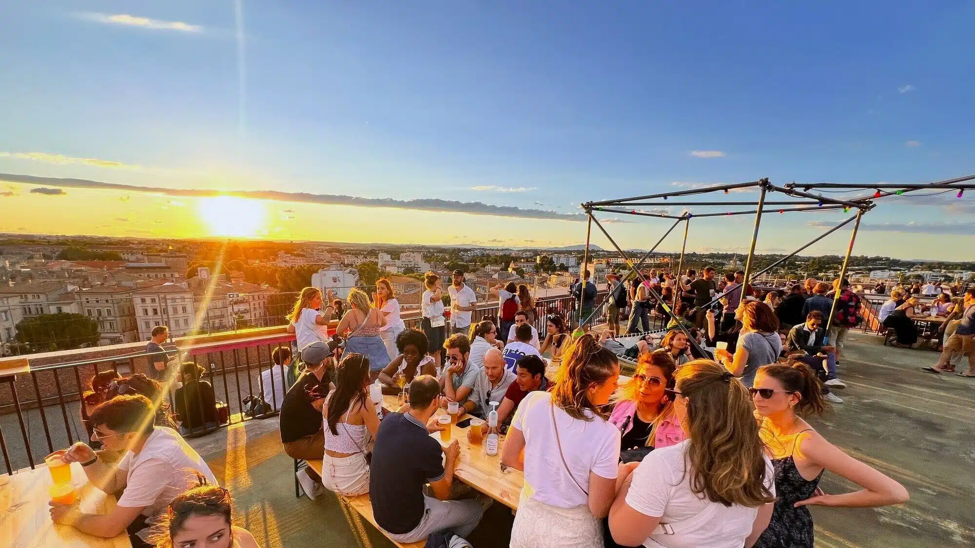 Rooftop festif à Montpellier oule festive sur un rooftop à Montpellier, profitant de l'ambiance musicale au coucher du soleil.