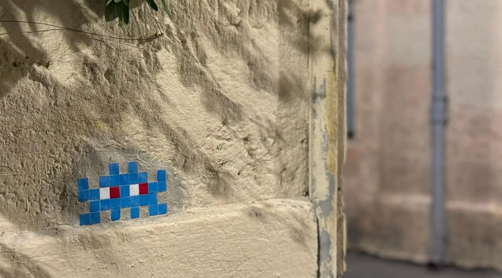 Découvrir le street art de l'Écusson. Mosaïque Space Invader bleue sur un mur de pierre, exemple de street art à Montpellier dans l'Écusson.